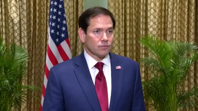 U.S. Secretary of State Marco Rubio standing in front of an American flag