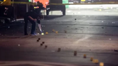 A Tallahassee police investigator examines evidence markers on Perry Street near Bragg Memorial Stadium.