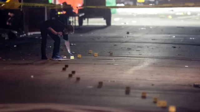 A Tallahassee police investigator examines evidence markers on Perry Street near Bragg Memorial Stadium.